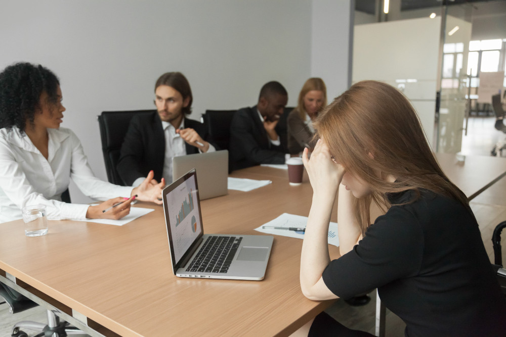 Líder mulher em reunião corporativa cercada de silêncio, ilustrando as barreiras invisíveis da falta de segurança psicológica na liderança feminina
