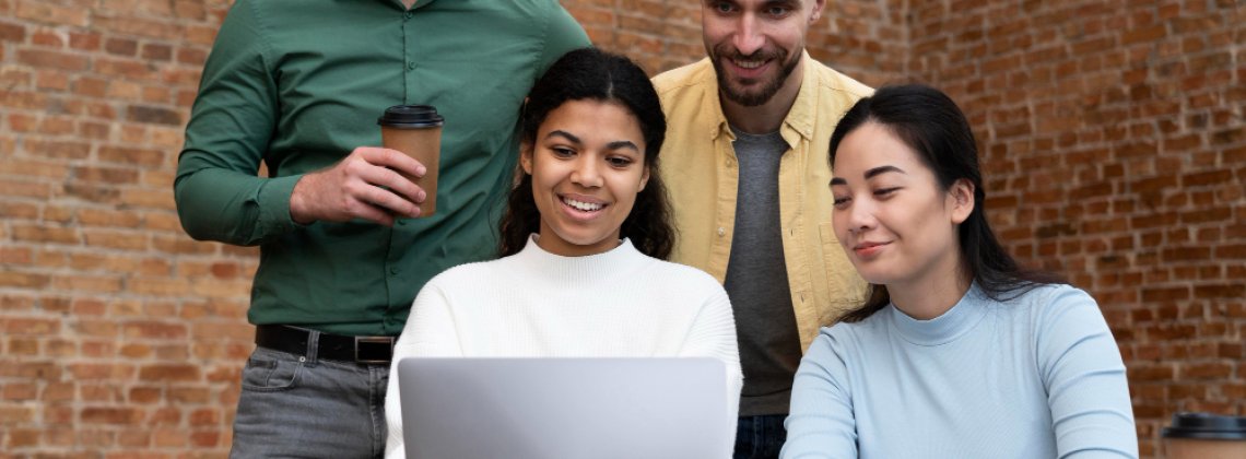Equipe de profissionais reunidos em colaboração diante de um laptop, simbolizando o desenvolvimento de equipes eficiente