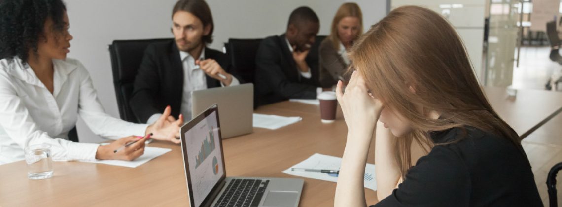 Líder mulher em reunião corporativa cercada de silêncio, ilustrando as barreiras invisíveis da falta de segurança psicológica na liderança feminina